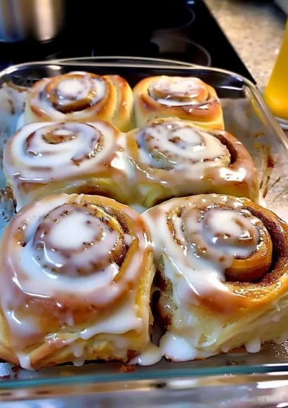 Freshly baked classic cinnamon rolls with icing on a wooden table