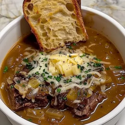 A delicious bowl of French onion beef short rib soup garnished with herbs.