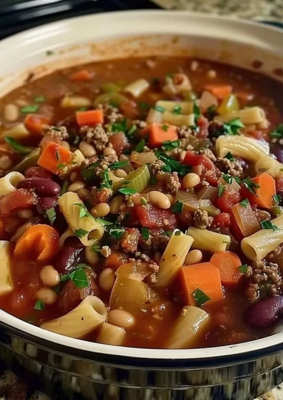 A steaming bowl of Pasta Fagioli with tender beans and pasta in a savory broth.