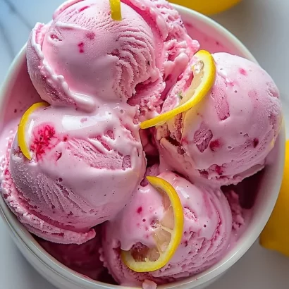 Delicious pink lemonade ice cream in a bowl topped with fresh lemon slices.