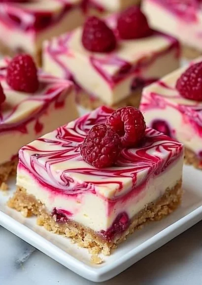 Delicious Raspberry Swirl Cheesecake Bars served on a plate with fresh raspberries.